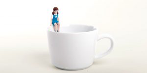 Fuchico in blue uniform sitting on the edge on a cup