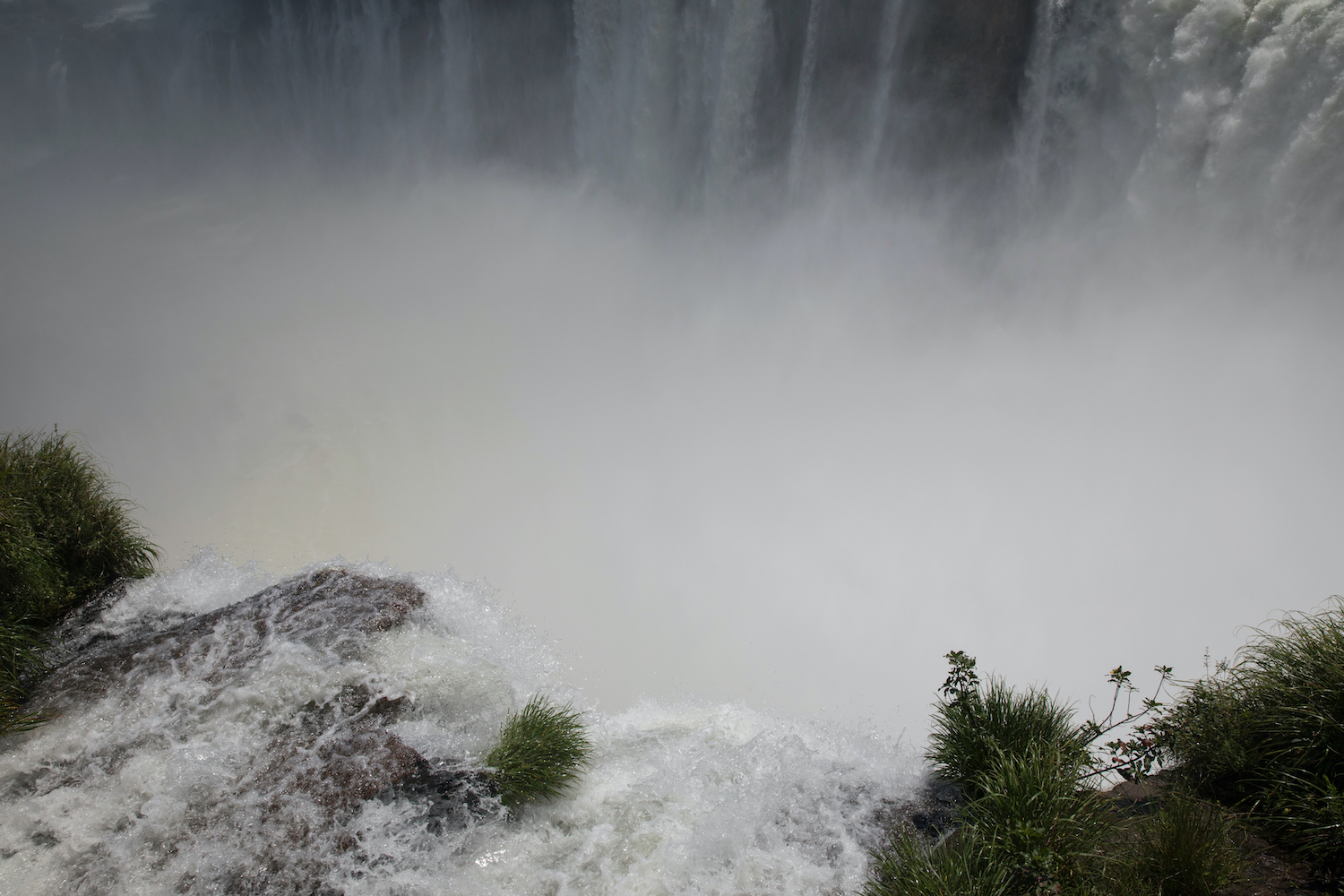 The unique view of the Iguazu waterfalls seen from Garganta del Diablo in Misiones jungle, Argentina. Vertigo. The white water flows and falls along the precipice. The beautiful mist and void.