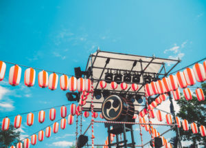 The stage of the Yagura with a big Japanese taiko drum Ojime blue sky background. Paper red-white lanterns Chochin Scenery for the holiday Obon when people dance of Bon Odori