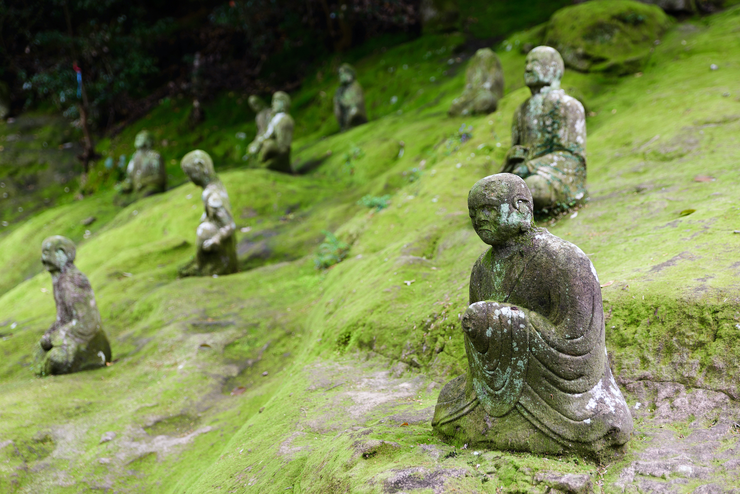 Kumamoto, Apr. 10, 2016: stone monks covered in spring moss at Reigando, the Miyamoto Musashi Cave, entrance before the major 2016 earthquake.