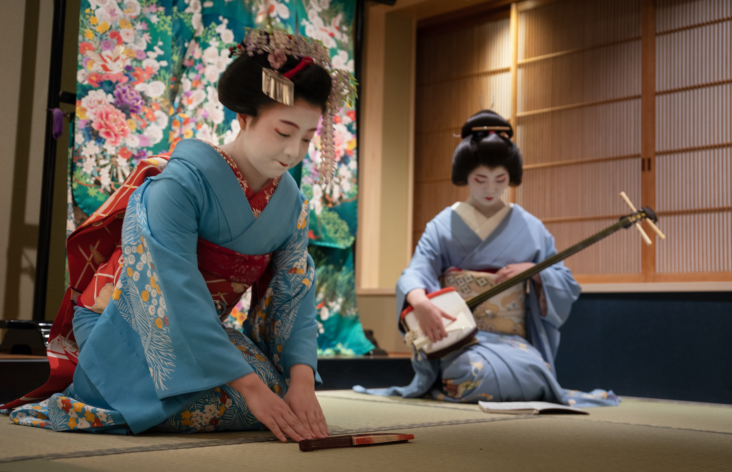 Kyoto, Japan - May 19, 2019: Maiko bows at the end of traditional performance in a small Japanese inn with geisha behind