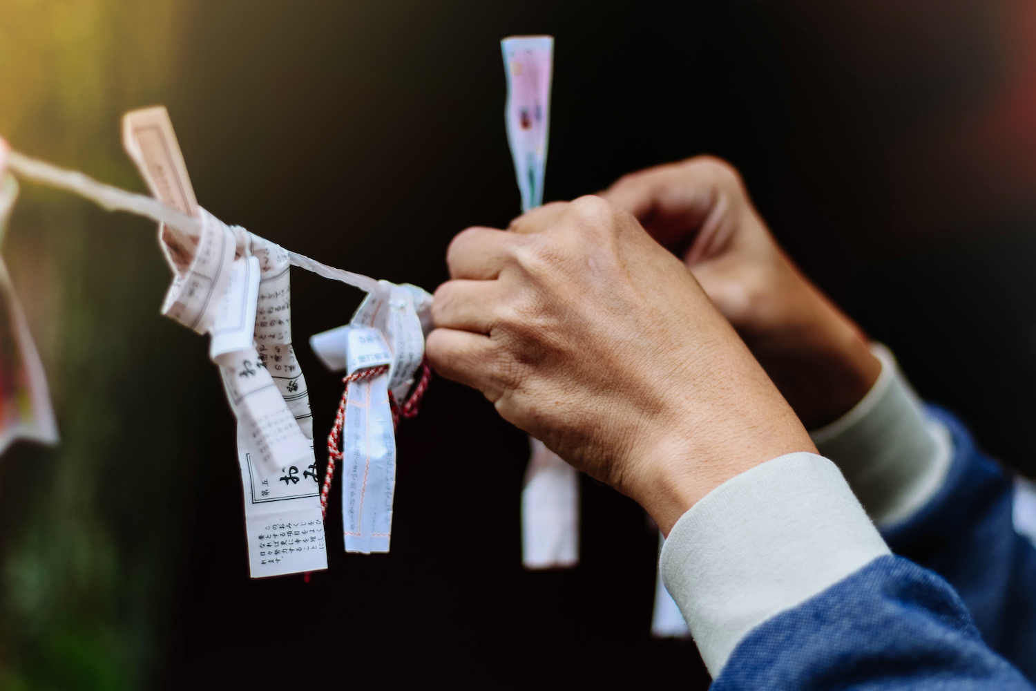 NIKKO, JAPAN - OCT 12,2018 : Close up of an unidentified man's hands puts messages with the wishes Omikuji Paper Fortune at the temple in Japan.