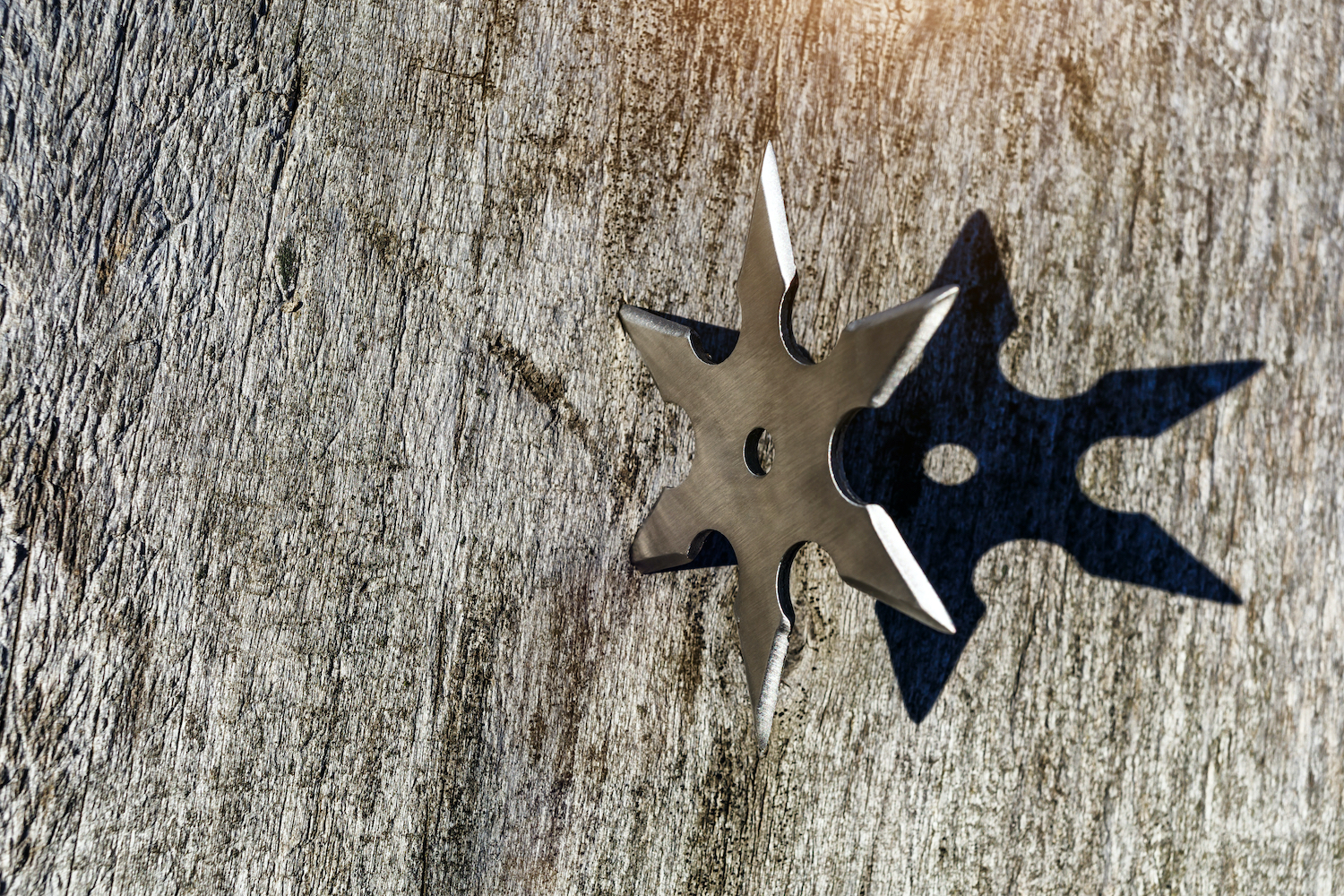 Shuriken (throwing star), a traditional Japanese ninja cold weapon stuck in the wooden background, Silver shuriken with a star shape. Samurai, throwing weapons