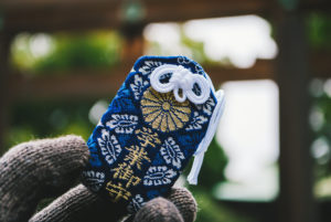 Omamori Japanese lucky charm holding in a hand on a cloudy day. The Japanese word in the picture says: Success in Education