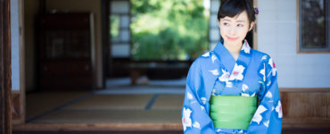 A woman in blue yukata, Japanese traditional casual summer dress, sits on the edge of veranda