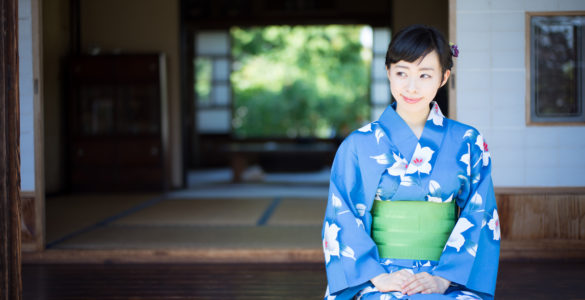 A woman in blue yukata, Japanese traditional casual summer dress, sits on the edge of veranda