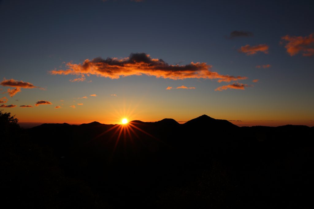 sunsetting in the shadowed mountains with orange cloud up there