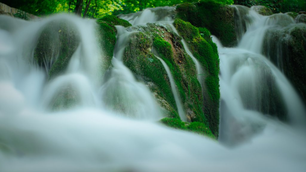 mountain stream with water splash over rocks covered with moss